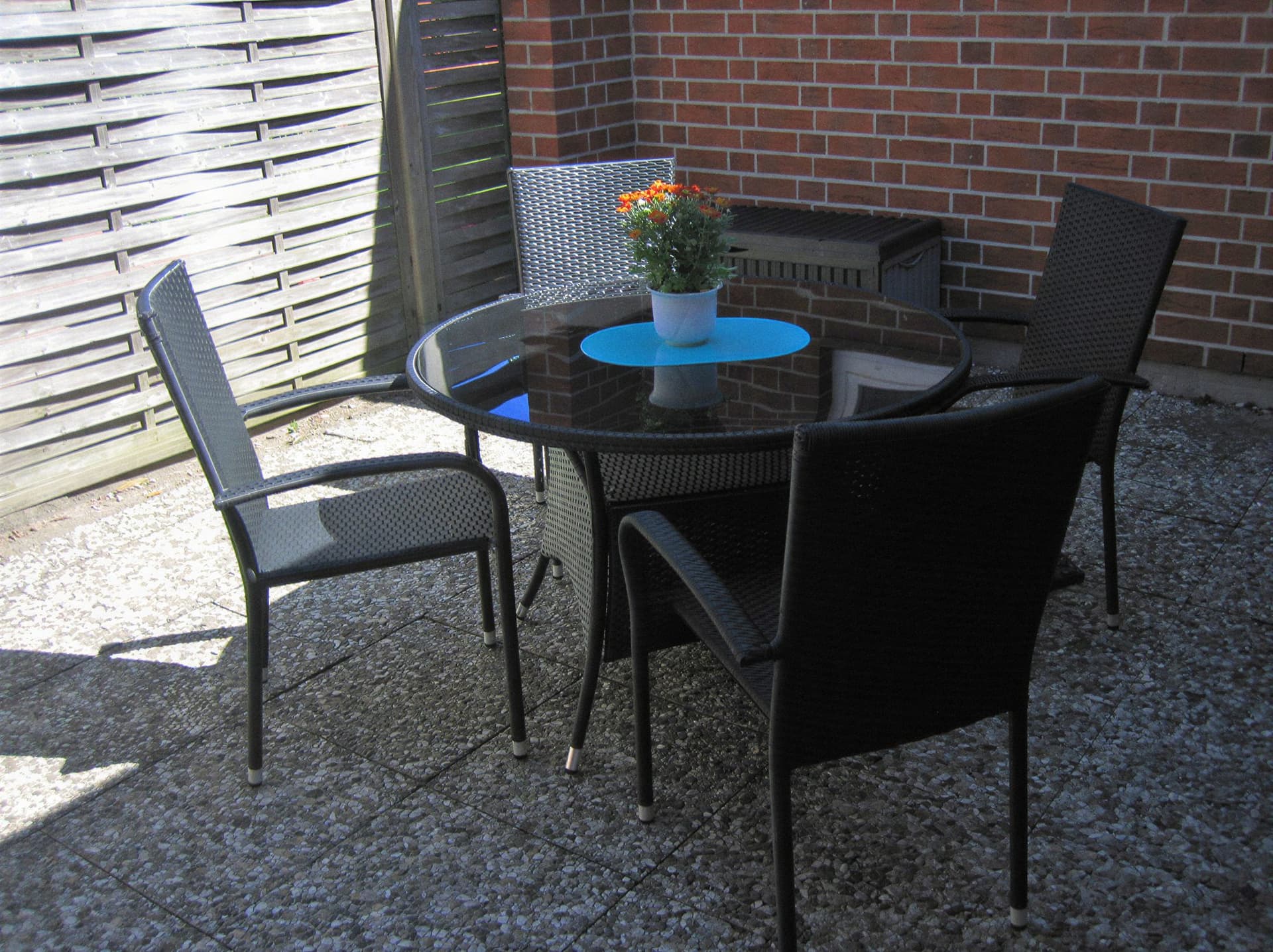Terrasse im Innenhof mit rundem Gartentisch und vier Stühlen
