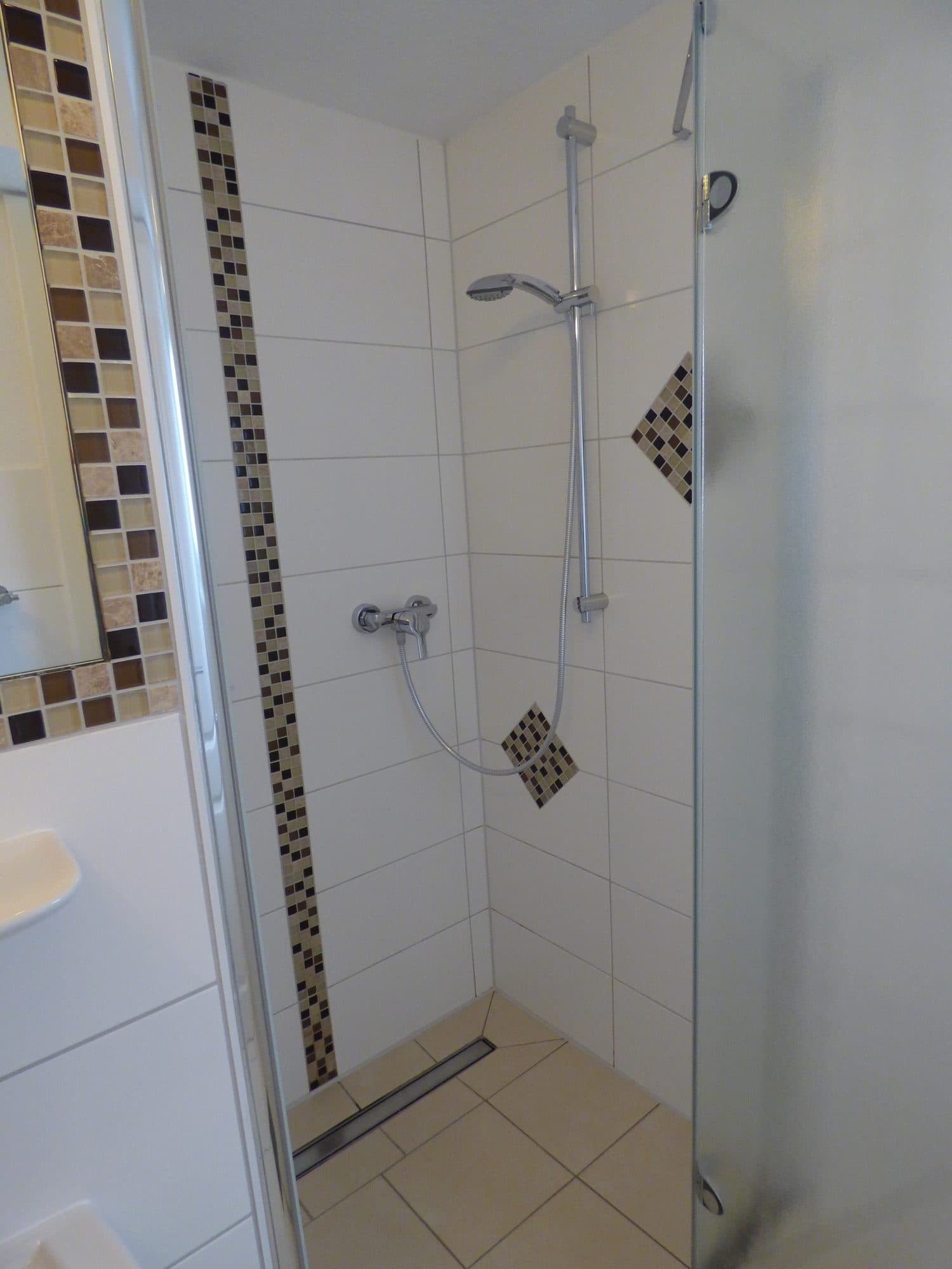 Dusche mit Glaswand und Mosaikfliesen