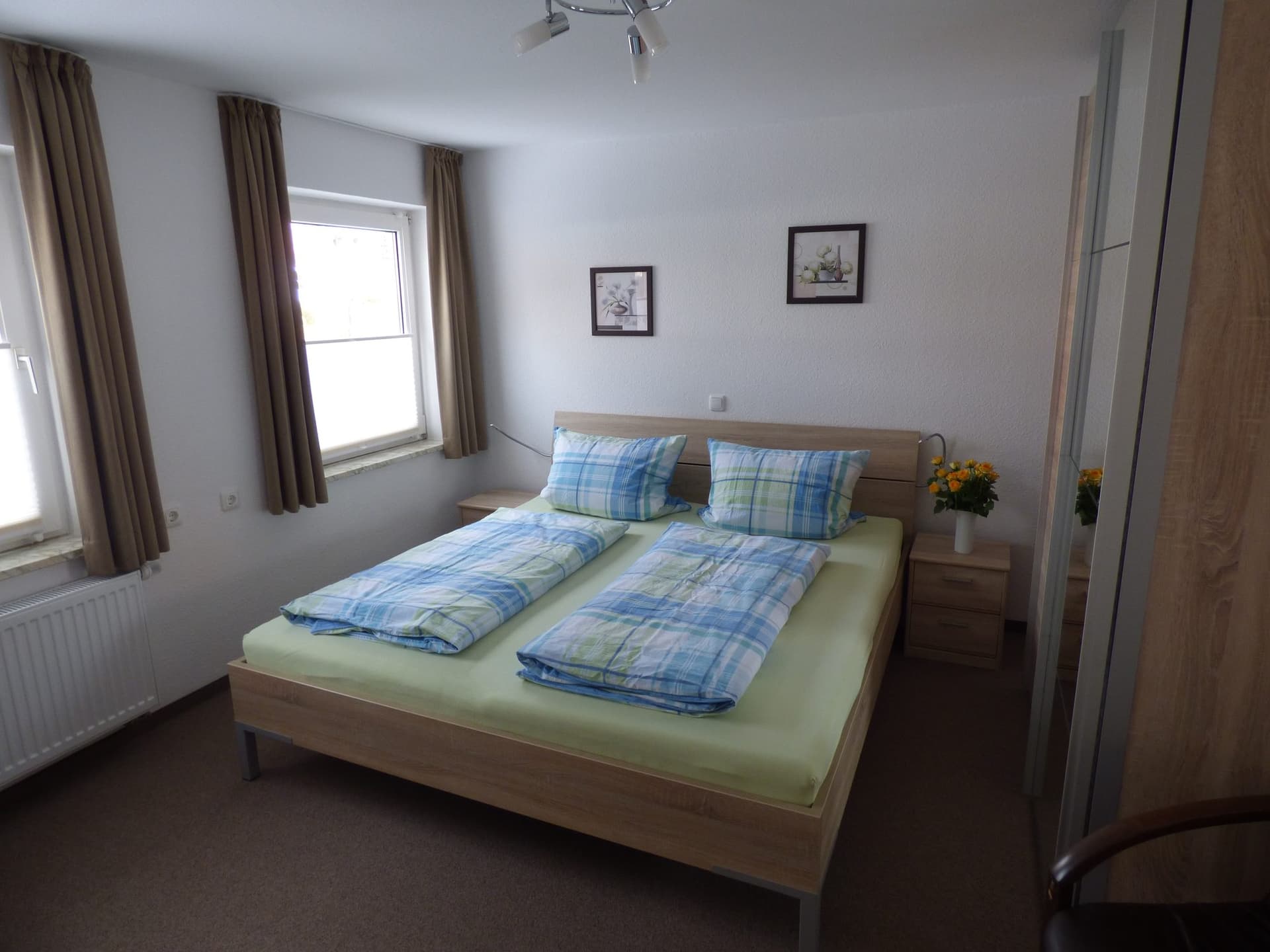 Schlafzimmer mit Doppelbett und blau karierter Bettwäsche