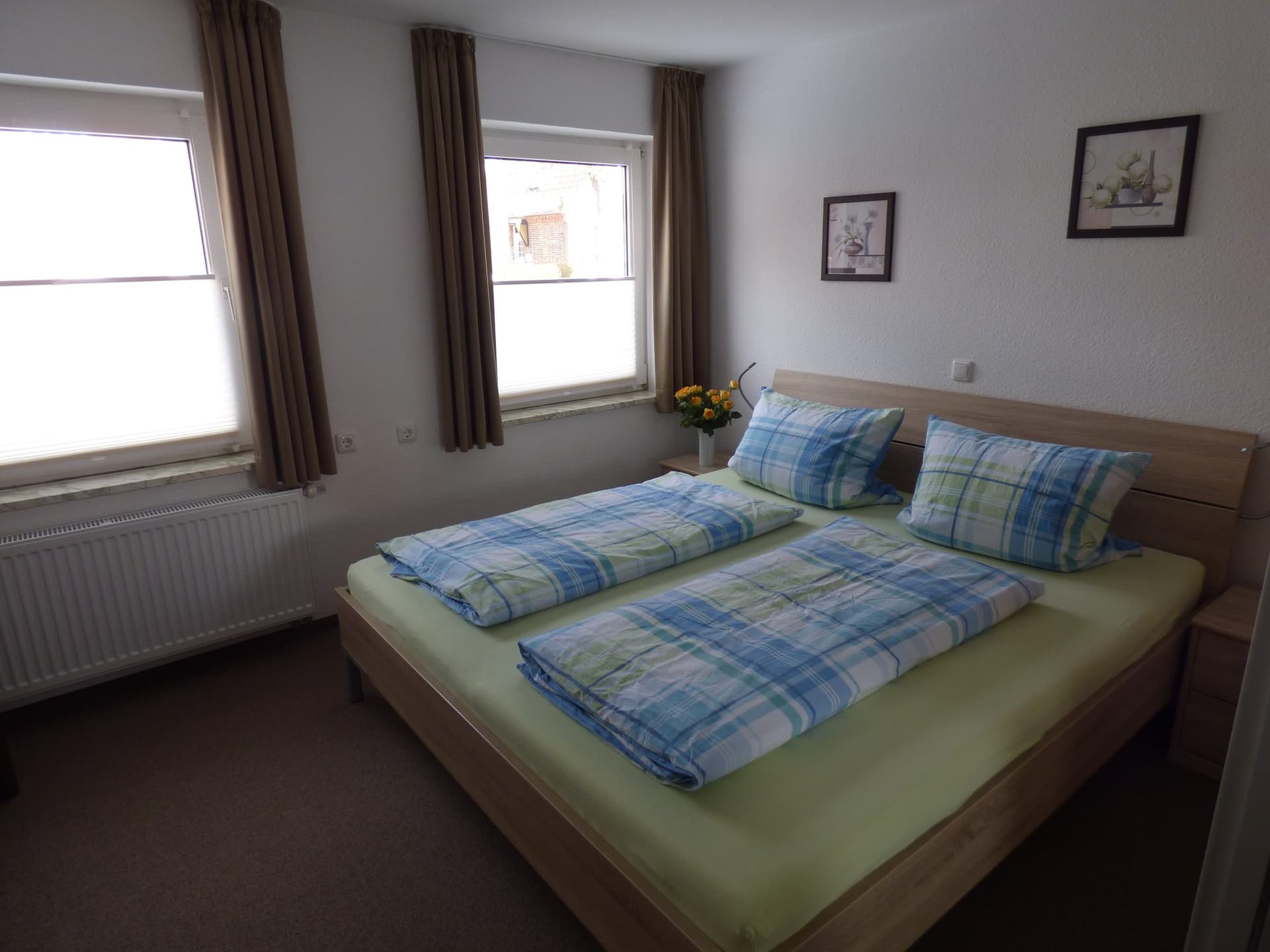 Doppelbett am Fenster, daneben Bilder an der Wand