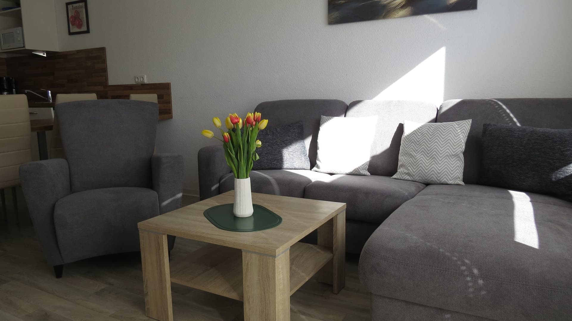 Wohnbereich mit Sofa, Sessel und Tulpen auf dem Couchtisch